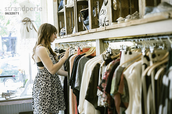 Mittlere erwachsene Frau sucht Kleiderstange in Vintage-Boutique