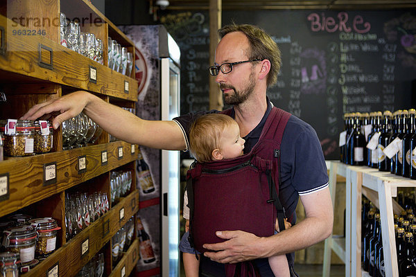 Vater mit kleiner Tochter beim Anblick von Gläsern im Laden
