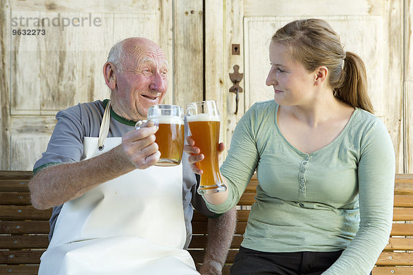 Senior Mann und junge Frau toasten mit Bier