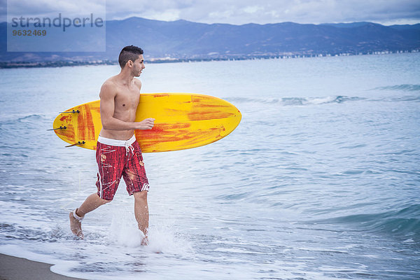 Junger Surfer mit Surfbrett am Strand  Cagliari  Sardinien  Italien