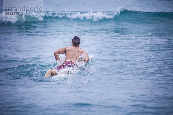 Junger Surfer auf dem Surfbrett im Meer liegend  Cagliari  Sardinien  Italien
