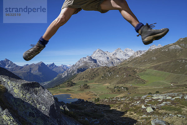 Beine eines männlichen Wanderers  der über Felsen springt  Lai da Fons  Kanton Graubünden  Schweiz