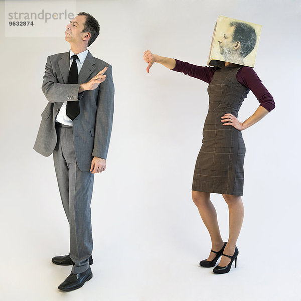 Businesswoman with mask showing thumbs down to businessman