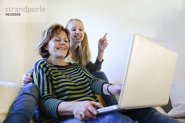 Grandmother and granddaughter working on laptop  smiling