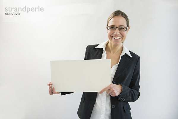 Portrait of businesswoman in black suit holding blank placard  smiling