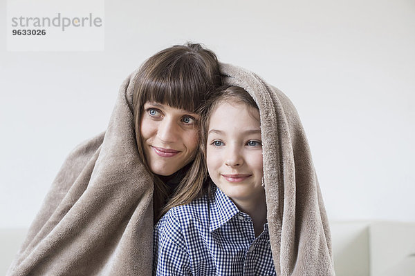 Mother and daughter covered with blanket  smiling