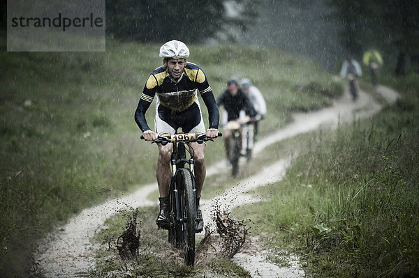 Mountain bikers riding in rain through mud  Italy