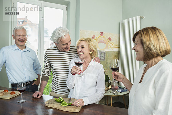 Senior group friends preparing lunch drinking wine