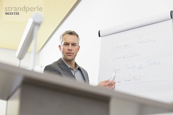 Businessman at speaker desk with flip chart in auditorium