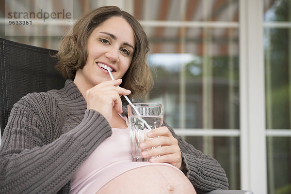Portrait pregnant woman smiling drinking straw