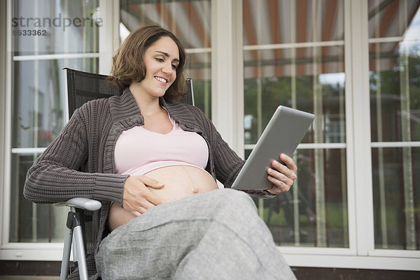 Tablet computer woman sitting pregnant smiling