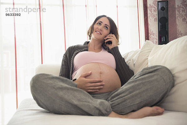 Woman phone talking sofa pregnant holding stomach