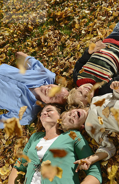 Family lying on autumn leaves  smiling
