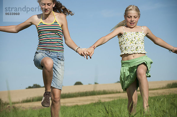 Two carefree happy young girls running meadow