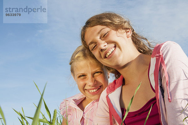 Two girls (10-11) (12-13) in meadow  smiling  portrait  close-up