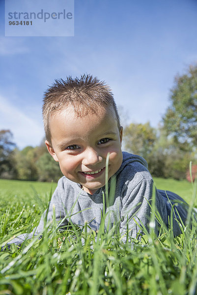 Small boy lying grass smiling happy