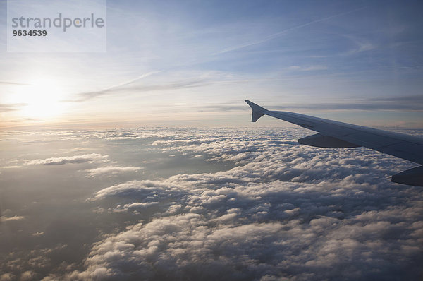 Aerial view of airplane flying over clouds at sunset