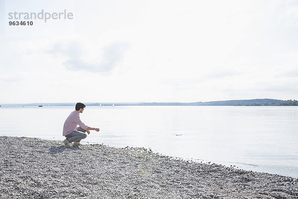 Man alone lake skimming stones