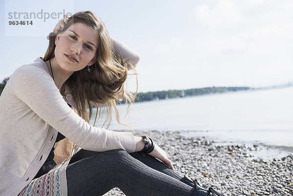 Portrait pretty young woman sitting lake shore