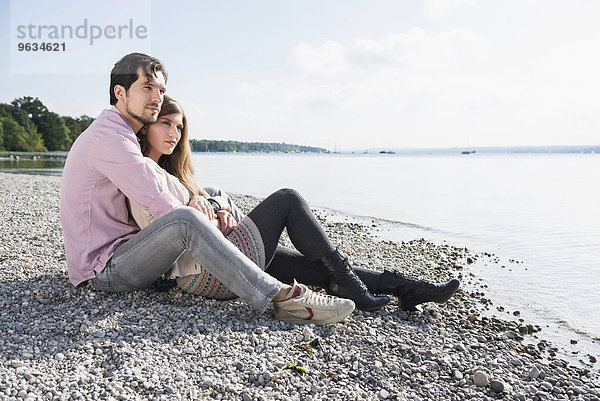 Loving young couple sitting shore lake