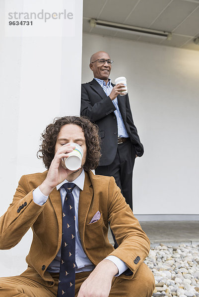 Two businessmen drinking coffee taking break
