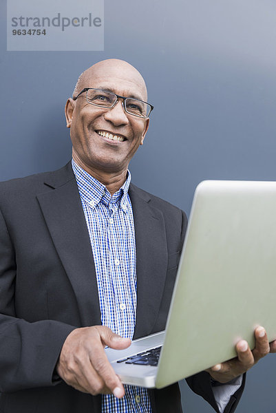 Happy African businessman holding laptop computer
