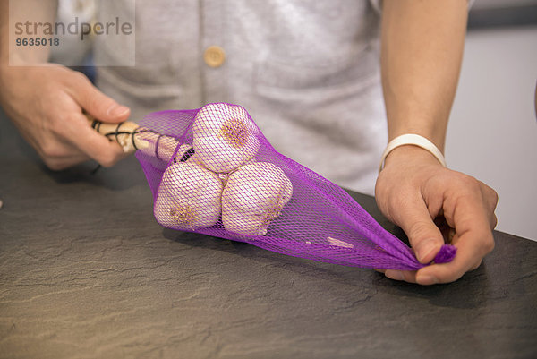 Young man garlic unpacked from the net bag at kitchen