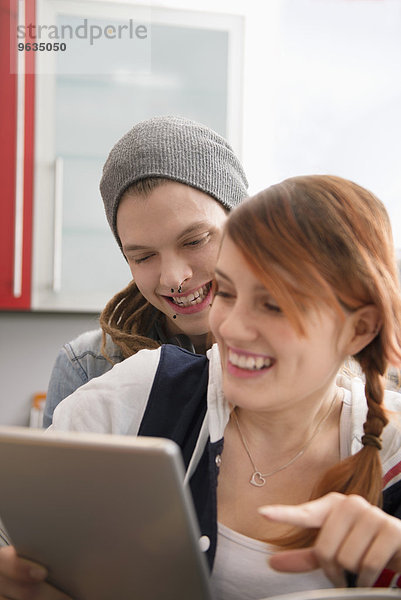 Couple laughing while using digital tablet