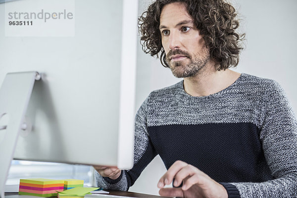 Businessman sitting at desk working on computer in office