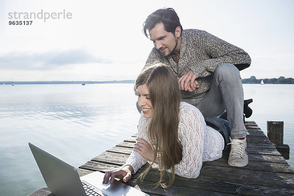 Smiling young couple outdoors working laptop