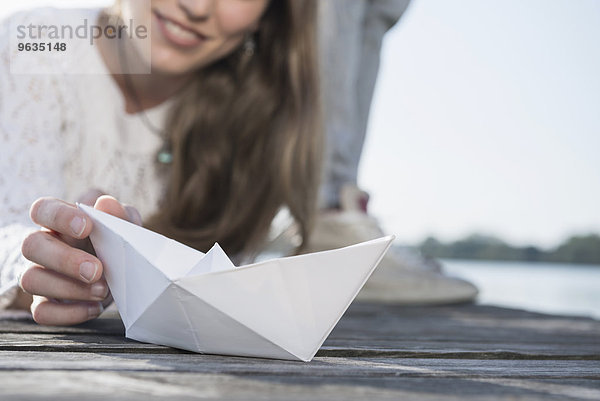 Close up woman holding white paper boat detail