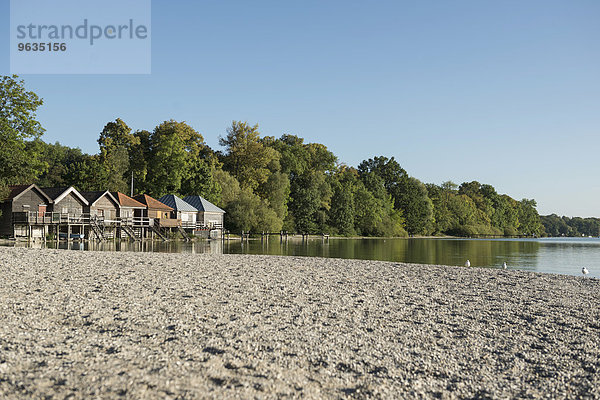 Lake shore boathouse autumn trees pebble beach