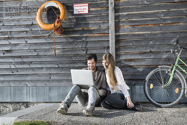 Wooden boathouse couple sitting using computer