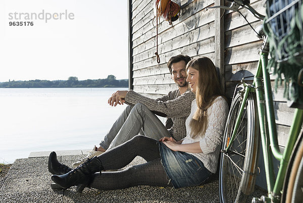 Young couple sitting relaxing lake boathouse