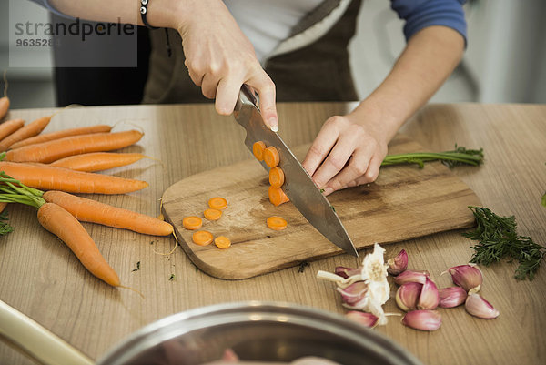 Woman slicing carrots in kitchen