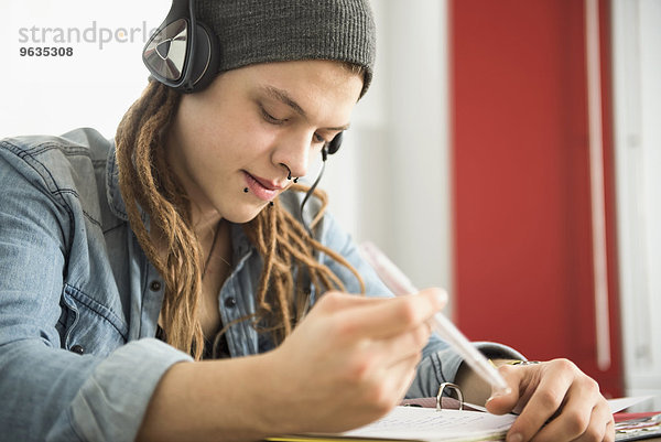 Young man wearing headphones and studying at home