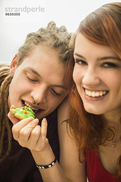 Young woman feeding cookie to her friend