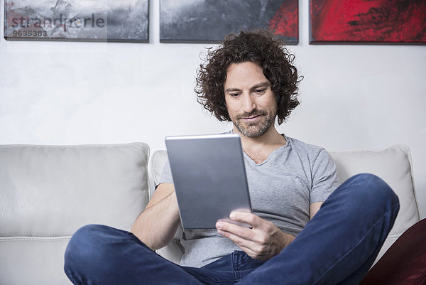 Man sitting on couch and using a digital tablet