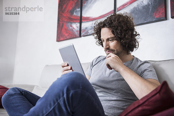 Man sitting on couch and using a digital tablet