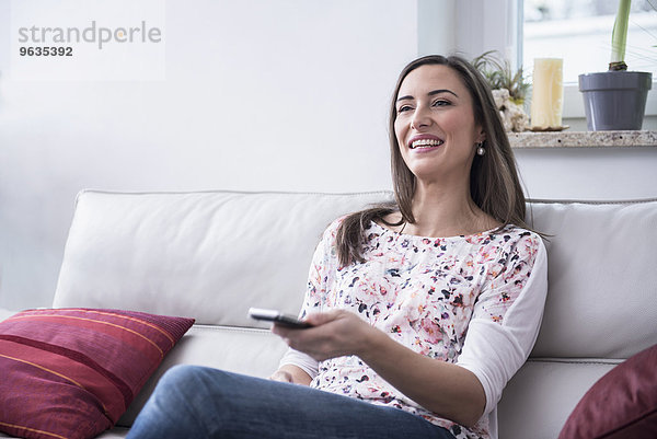 Beautiful woman changing television channel with remote control