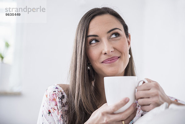 Beautiful woman drinking cup of coffee at sofa
