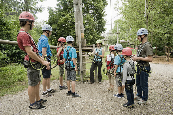Young woman giving instruction to group of people for climbing crag
