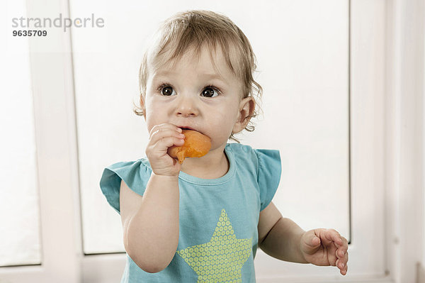 1 year old baby girl holding eating fruit