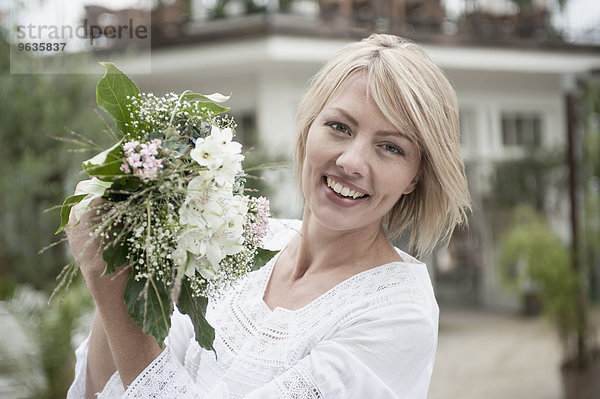 Portrait blond woman celebrating holding bouquet