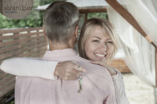 Loving couple hugging garden woman holding keys