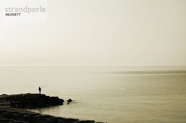 Man fishing rocks ocean sea Italy alone morning