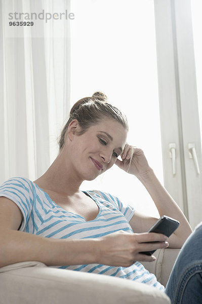 Attractive young blond pregnant woman reading SMS