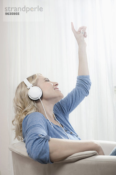Young blond woman sitting chair listening music