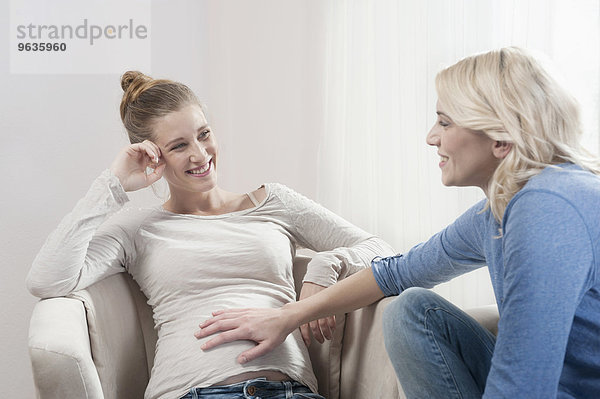 Pregnant woman girlfriend talking touching stomach