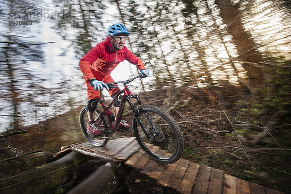 Mountain biker crossing wooden bridge in a forest